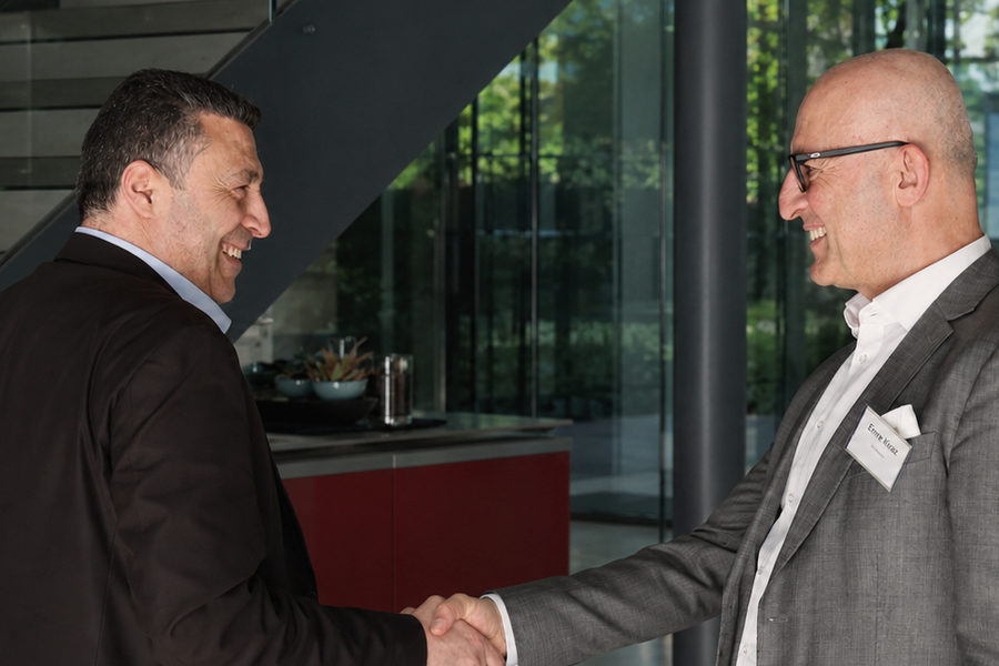 Zwei Geschäftsleute geben sich im Foyer eines Bürogebäudes die Hand.